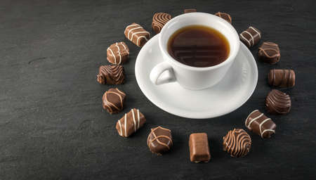 Beautiful Creative Chocolate Sweets on Natural Black Stone Background. Mix of Chocolates in Round Frame Shape with Place for Textの写真素材