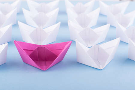 One Unique Pink Paper Boat among Many Ones. Different Paper Ships as Individuality and Leadership Conceptの写真素材