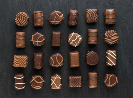 Beautiful Creative Chocolate Sweets on Natural Black Stone Background. Mix of Chocolates Top View and Flat Layの写真素材