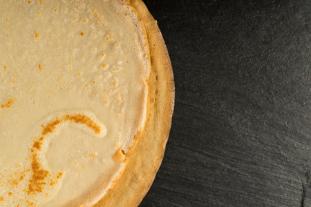Thin Pancakes on Black Stone Background Top View. Fresh Homemade Crepes or Flatbread Flat Lay with...