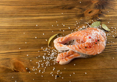 Raw Salted Salmon Steak on Natural Old Wooden Board. Thick Pieces of Fresh Red Fish or Trout Top View with Copyspaceの写真素材