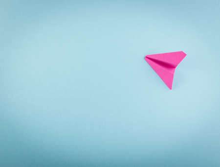 Pink Paper Plane or Paper Airplane Origami on Blue Background Top View with Place for Textの写真素材
