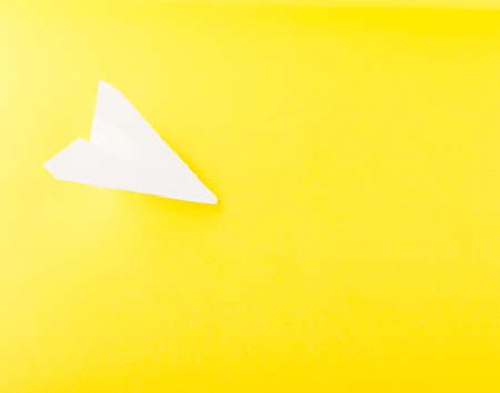 White Paper Plane or Paper Airplane Origami on Yellow Background Top View with Place for Textの写真素材
