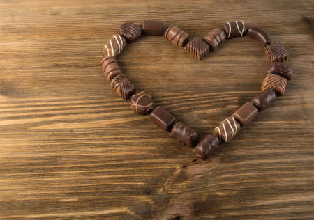 Beautiful Creative Chocolate Heart on Natural Wooden Table Background. Mix of Chocolates Top View and Flat Lay with Place for Textの写真素材