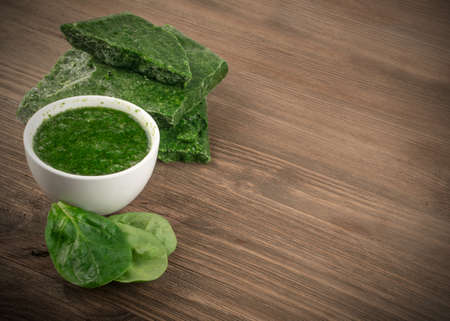 Fresh and Unfrozen Green Baby Spinach or Spinacia Oleracea Leaves. Leafy Green Vegetable on Rustic Wooden Background with Place for Textの写真素材