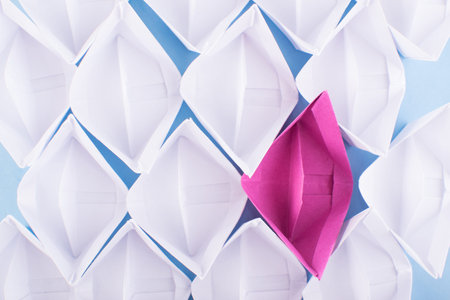 One Unique Pink Paper Boat among Many Ones. Different Paper Ships as Think Different and Creativity Conceptの写真素材