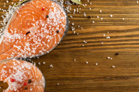 Raw Salted Salmon Steak on Natural Old Wooden Board. Thick Pieces of Fresh Red Fish or Trout Top View with Copyspaceの写真素材