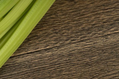 Raw green celery stalks on wood background top view. Fresh organic vegetables on old wooden rustic...