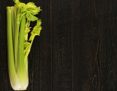 Raw green celery stalks on wood background top view. Fresh organic vegetables on old wooden rustic table with place for text or copyspaceの写真素材