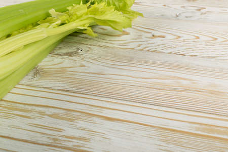 Raw green celery stalks on wood background top view. Fresh organic vegetables on old wooden rustic table with place for text or copyspaceの写真素材