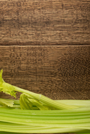 Raw green celery stalks on wood background top view. Fresh organic vegetables on old wooden rustic...
