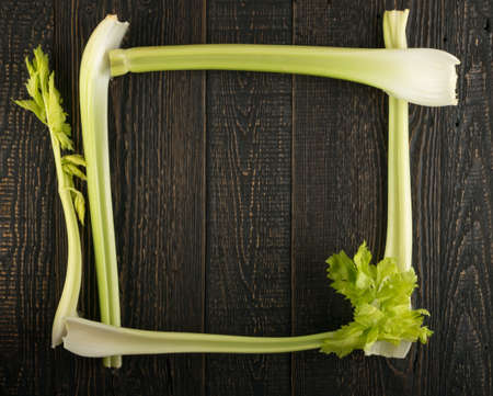 Raw green celery stalks on wood background top view. Fresh organic square vegetable frame on old wooden rustic table with copyspaceの写真素材