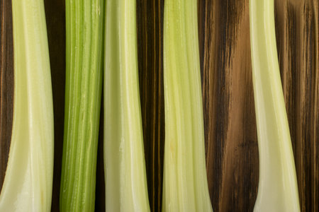 Raw green celery stalks on wood background top view. Fresh organic vegetables on old wooden rustic...