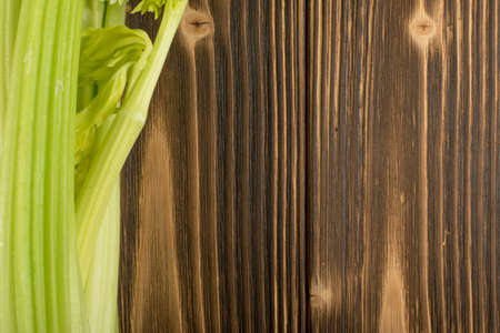 Raw green celery stalks on wood background top view. Fresh organic vegetables on old wooden rustic table with place for text or copyspaceの写真素材