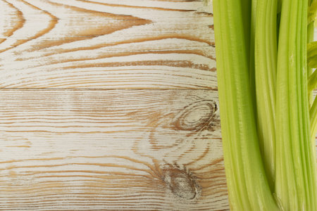 Raw green celery stalks on wood background top view. Fresh organic vegetables on old wooden rustic table with place for text or copyspaceの写真素材