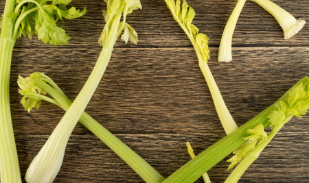 Raw green celery stalks on wood background top view. Fresh organic vegetables on old wooden rustic...