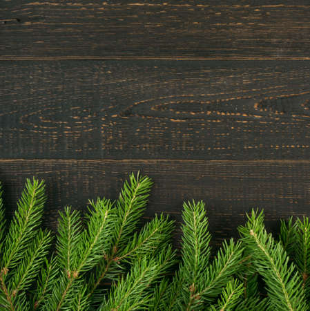 Christmas background with fir branches on wooden backdrop flat lay and top view. Yuletide floral frame decoration with copy space. Creative xmas tree border for New Year greeting cardの写真素材