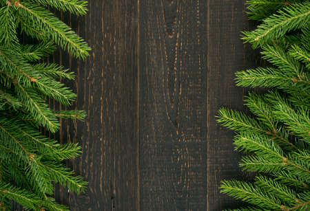 Christmas background with fir branches on wooden backdrop flat lay and top view. Yuletide floral frame decoration with copy space. Creative xmas tree border for New Year greeting cardの写真素材