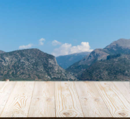 Wood table outside with mountain view in beautiful summer day. Rustic wooden desk outdoor background. Template mock up with countertop for product advertisingの写真素材