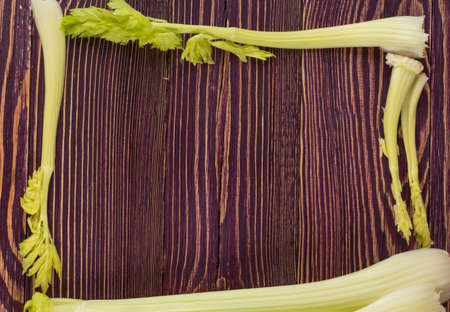 Raw green celery stalks on wood background top view. Fresh organic square vegetable frame on old wooden rustic table with copyspaceの写真素材
