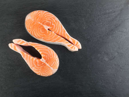 Slice of Raw Salmon Steak on Natural Black Background. Thick Piece of Fresh Red Fish or Trout Top View with Place for Textの写真素材