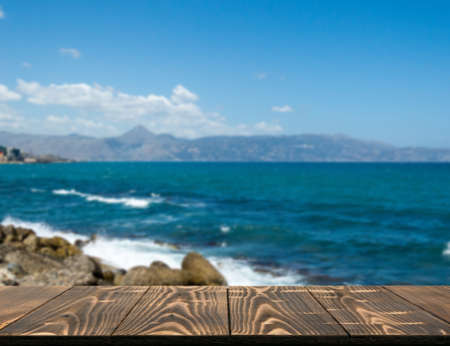 Wood table outside with seaview in beautiful summer day. Rustic wooden desk outdoor on sea view background. Template mock up with countertop for product advertisingの写真素材