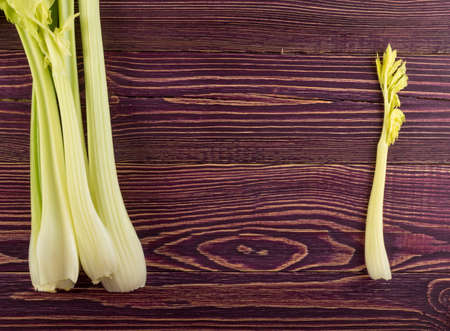 Raw green celery stalks on wood background top view. Fresh organic vegetables on old wooden rustic table with place for text or copyspaceの写真素材