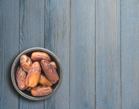 Dried Dates in Round Bowl on Wooden Background Top View. Fruits of Date Palm or Phoenix Dactylifera...