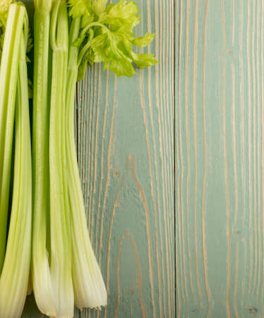 Raw green celery stalks on wood background top view. Fresh organic vegetables on old wooden rustic table with place for text or copyspaceの写真素材