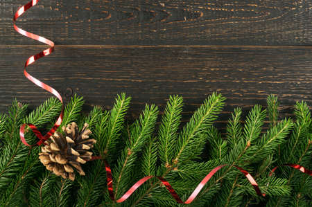 Christmas background with fir branches on wooden backdrop flat lay and top view. Yuletide floral frame decoration with copy space. Creative xmas tree border for New Year greeting cardの写真素材