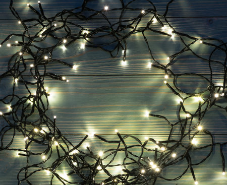Christmas Light on Blue Wooden Background Top View with Copyspace. Garland Lights on Vintage Wood...