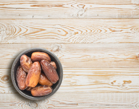 Dried Dates in Round Bowl on Wooden Background Top View. Fruits of Date Palm or Phoenix Dactylifera...