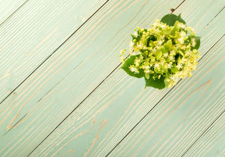 Linden Flowers on Wooden Background. Beautiful Summer Bouquet over Wood Table Texture. Tilia Blossom with Place for Textの写真素材