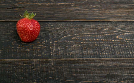 Fresh Beautiful Strawberry on Old Vintage Wooden Background with Copyspace. Dark Wood Table Desk Board Texture with Ripe One Berry Top Viewの写真素材