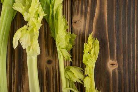 Raw green celery stalks on wood background top view. Fresh organic vegetables on old wooden rustic table with place for text or copyspaceの写真素材
