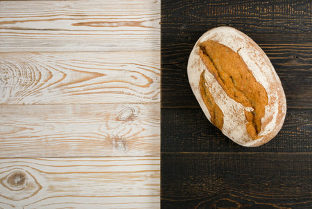 Homemade Freshly Baked Traditional Bread on Light Wooden Table Top View with Copyspace. Whole Loaf...