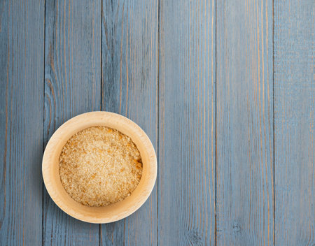 Heap of Bread Crumbs in Wooden Bowl Top View. Crushed Rusk Bread Crumbs or Panko on Wood Tableの写真素材