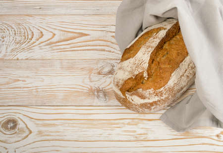 Homemade Freshly Baked Traditional Bread on Light Wooden Table Top View with Copyspace. Whole Loaf of Rustic Italian Cereal Bread Made of Sourdough Dough with Space for Textの写真素材