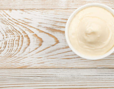 Homemade Olive Mayonnaise or Mayo Sauce in Small White Bowl Close Up. Macro Photo of Greek Yogurt, Sour Cream, Cheese Pudding or Aioli on Wooden Background Top Viewの写真素材