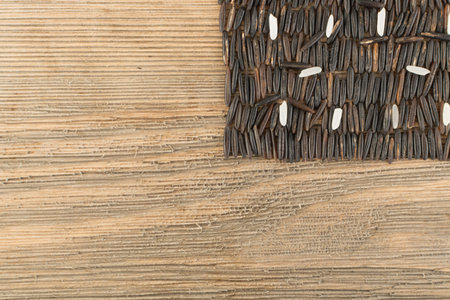 Raw Black Wild Rice on Old Wood Background Top View. Healthy Dietetic Canada Bio Rice Cereal Texture with Place for Textの写真素材