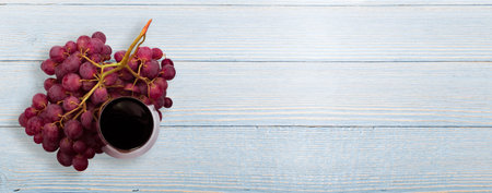 Glass of red wine and grapes on blue wooden table top view