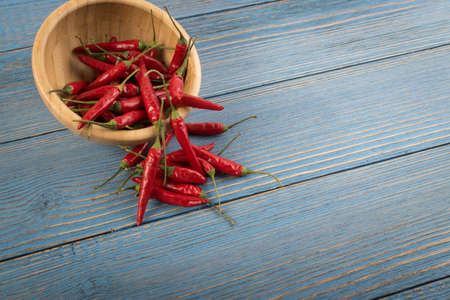 Very Hot Chili Peppers in Bowl on Rustic Wooden Background Top View. Red Spicy Chilli Peppers Pattern or Backdrop for the Indian Menu for Oriental Food Designの写真素材