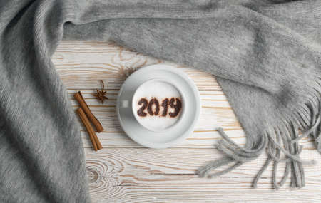 2019 Macchiato or Latte Cappuccino on Rustic Wooden Background with Grey Plaid. Hot Coffee Cup with Cream Milk Foam on Wood Table Top Viewの写真素材