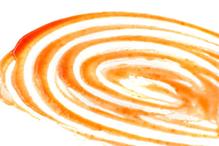 Spreaded tomato sauce, ketchup or catchup spiral isolated on white background. Smeared puddles of catsup round texture spot top view with place for textの写真素材