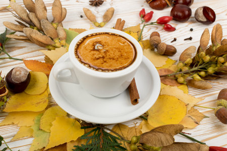 Floral autumn background with a mug of coffee surrounded by leaves, autumn tree seeds and fragrant...