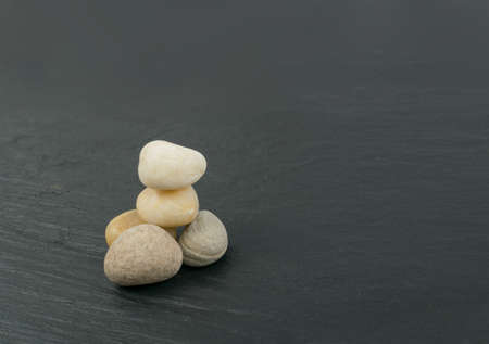 Stacked stones in equilibrium as philosophy meditation concept. White cairns or pebble tower on black stone backgroundの写真素材