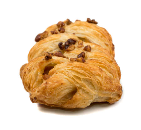 Sweet braided puff pastry isolated or pate feuilletee on white background. Fresh phyllo pastry with jam inside and macadamia nuts close upの写真素材