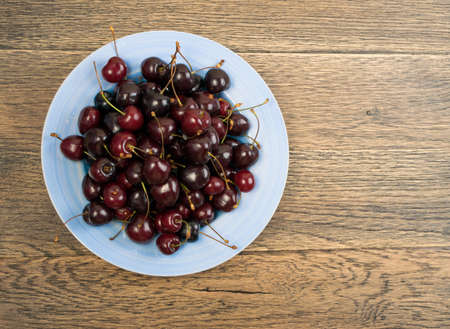 Fresh red cherry on old wooden background with copy space for design montage or mockup. Rustic wood table desk board texture with sweet cherries close upの写真素材