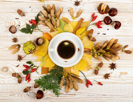 Floral autumn background with a mug of coffee surrounded by leaves, autumn tree seeds and fragrant...