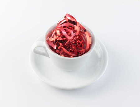 Scarlet serpentine in white cup as christmas drink concept. Festive mug with shiny red ribbon tangle